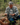 Man in a forest examining mushrooms with a basket full of them